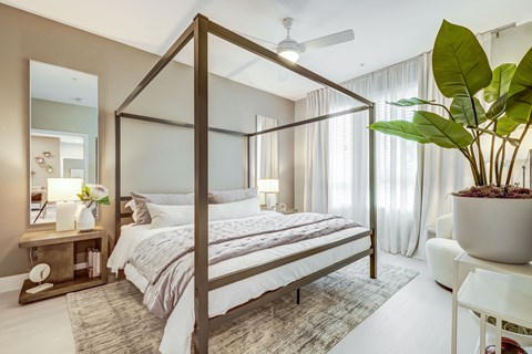 A bedroom with a four poster bed and a potted plant.